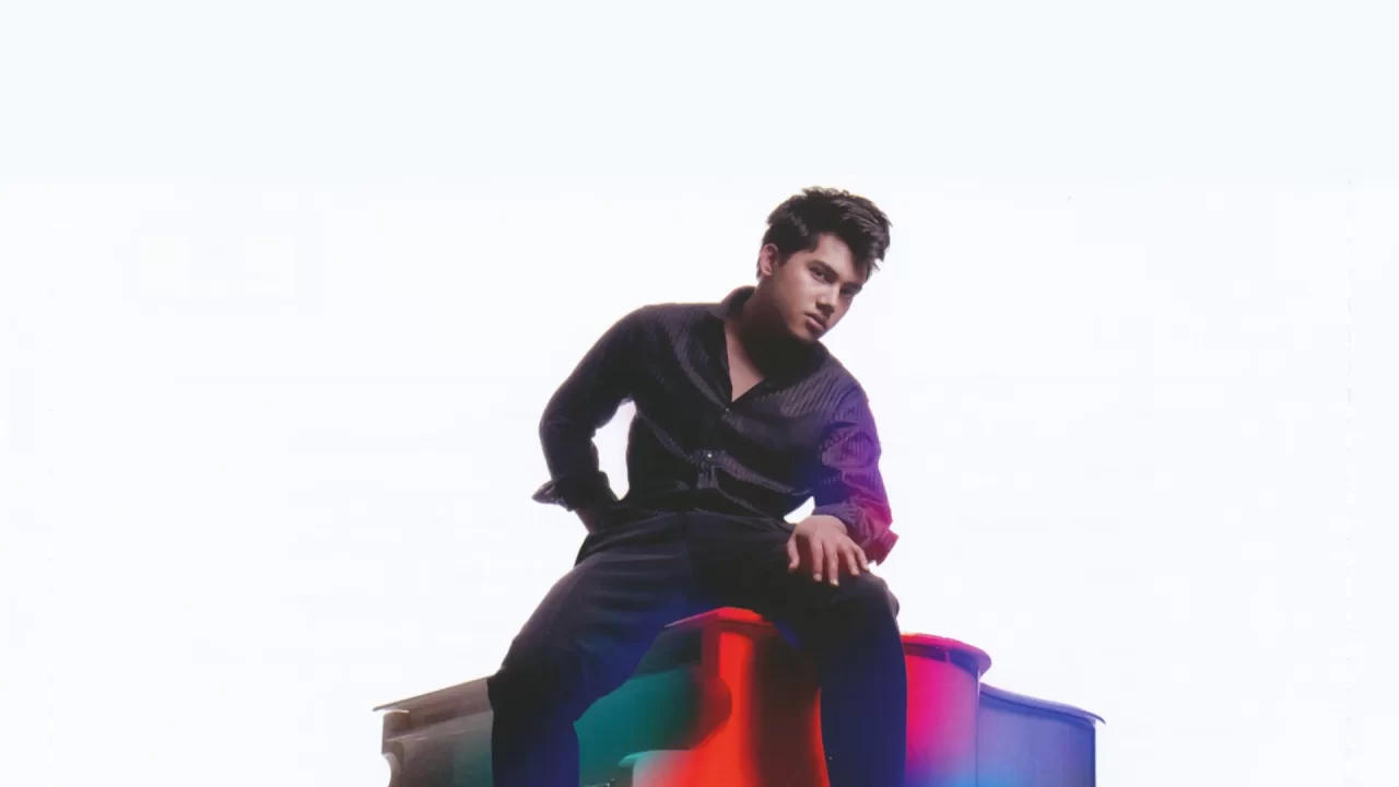 Benyamin Nuss Plays Uematsu (Featured Art) - Nuss pictured here sitting on a piano with colorful spotlights on it.