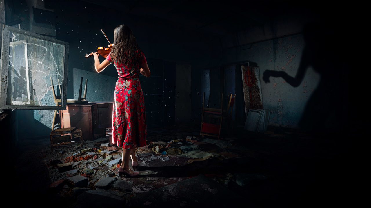 A woman in a red dress plays the violin in a dilapidated room