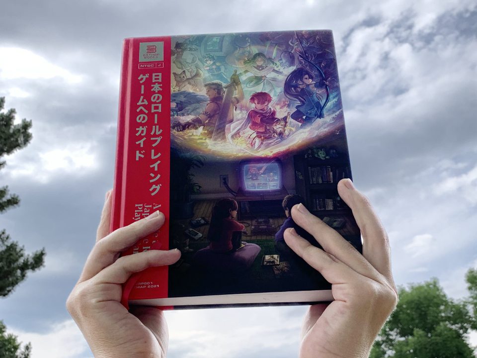 A guide to Japanese Role-Playing Games held aloft Zelda-style with a dramatic sky in the background.