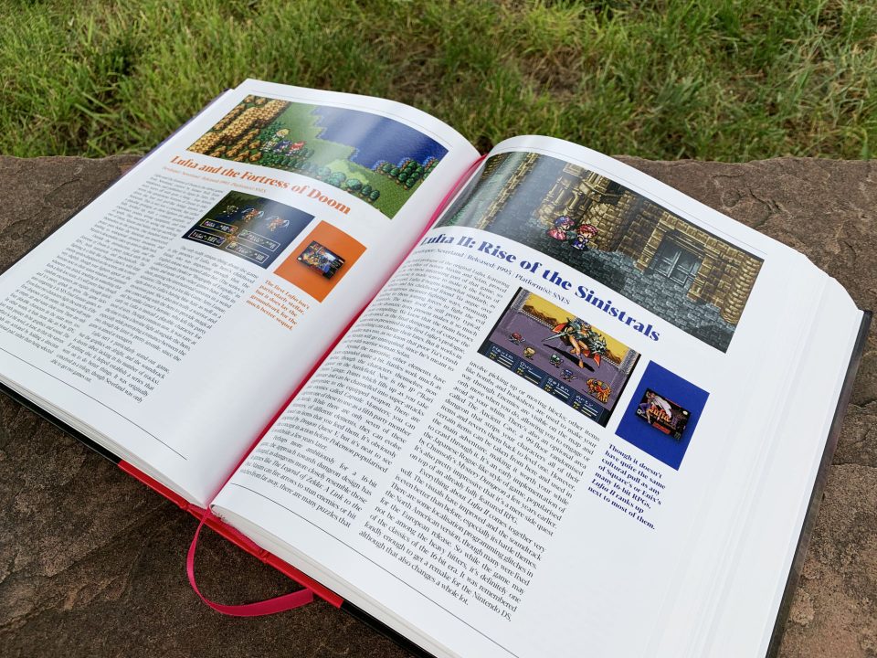 A Guide to Japanese Role-Playing Games lies open on a stone surface to the Lufia entries with some green grass in the background.