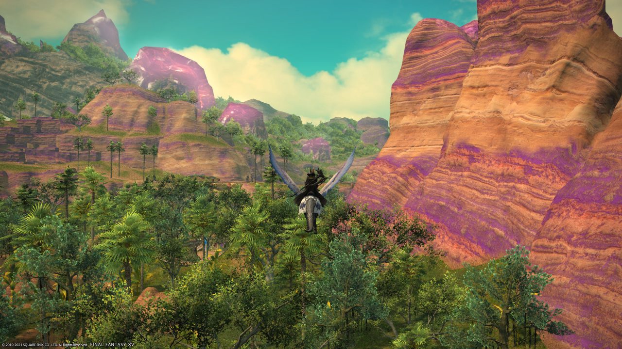 A Warrior of Light flying on a mount around Thavnair in Final Fantasy XIV: Endwalker. The cliffsides are purple and yellow, and the ground is adorned with lush foliage and trees.
