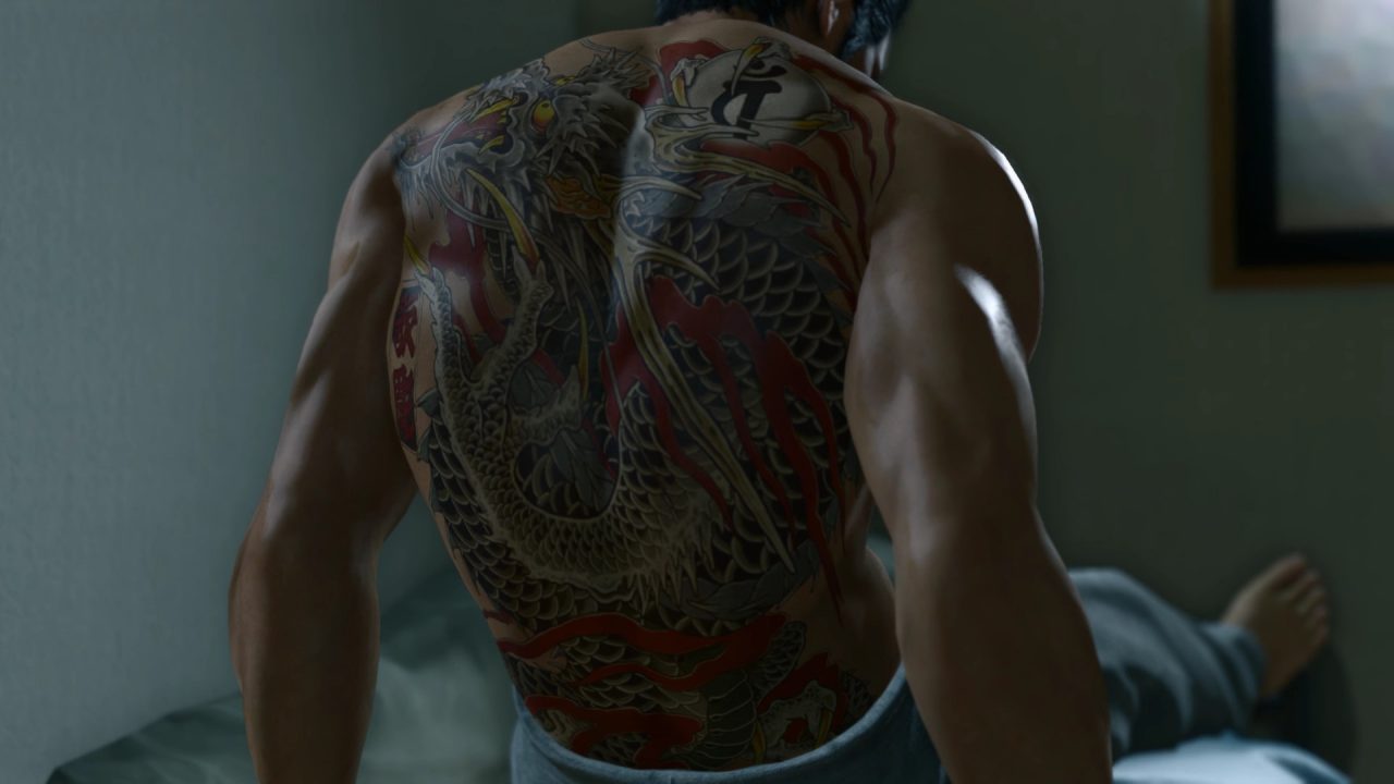 Yakuza Kiwami 2 screenshot looking at Kiryu's full back dragon tattoo as he sits up in a dimly-lit bedroom.