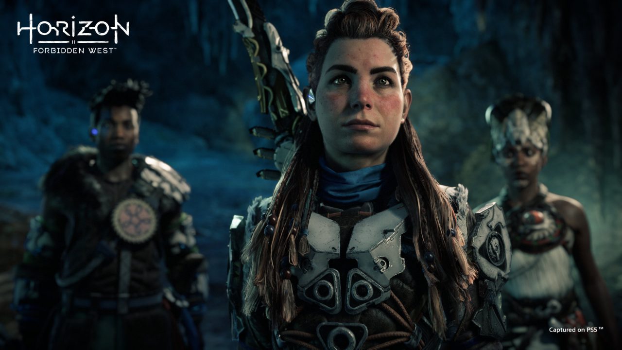 Horizon Forbidden West screenshot of Aloy (center), Varl (left), and Zo (right) looking right at the camera as they prepare to enter a cauldron.