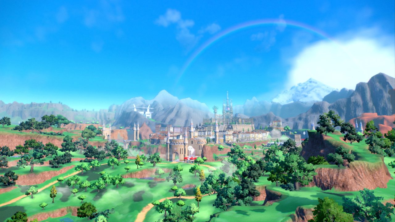 Pokémon Scarlet & Violet Screenshot of an aerial view of a lush, hilly land with a city nestled in the mountains.