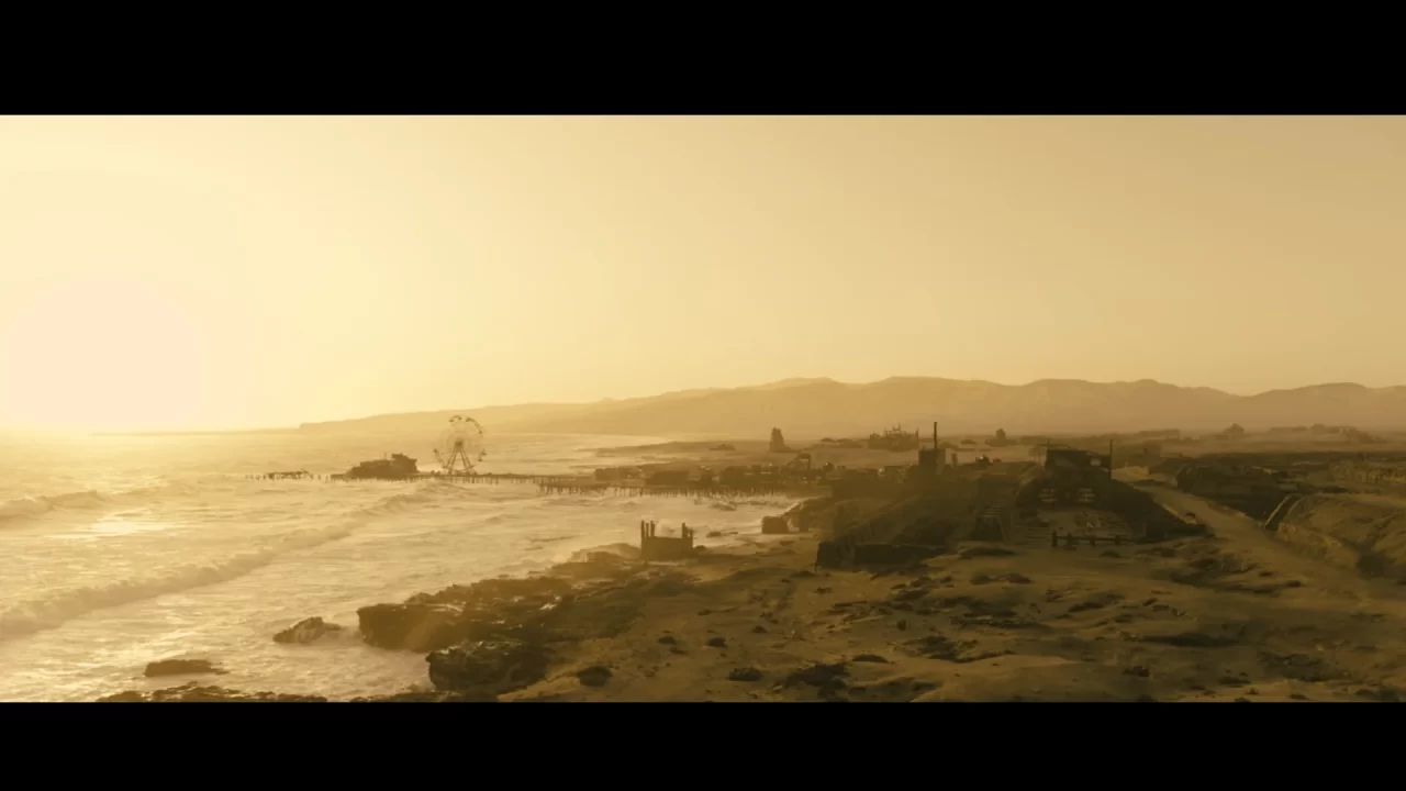 An aerial view of the wasteland of Santa Monica pier, with few structures and ferris wheel remnants remaining.