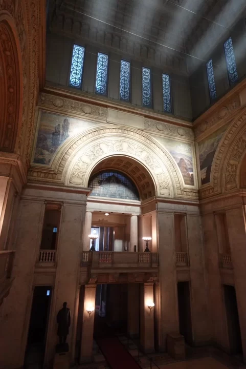 Photo of the interior of the National Diet Building. A large stone arch stands over a door and raised platform.