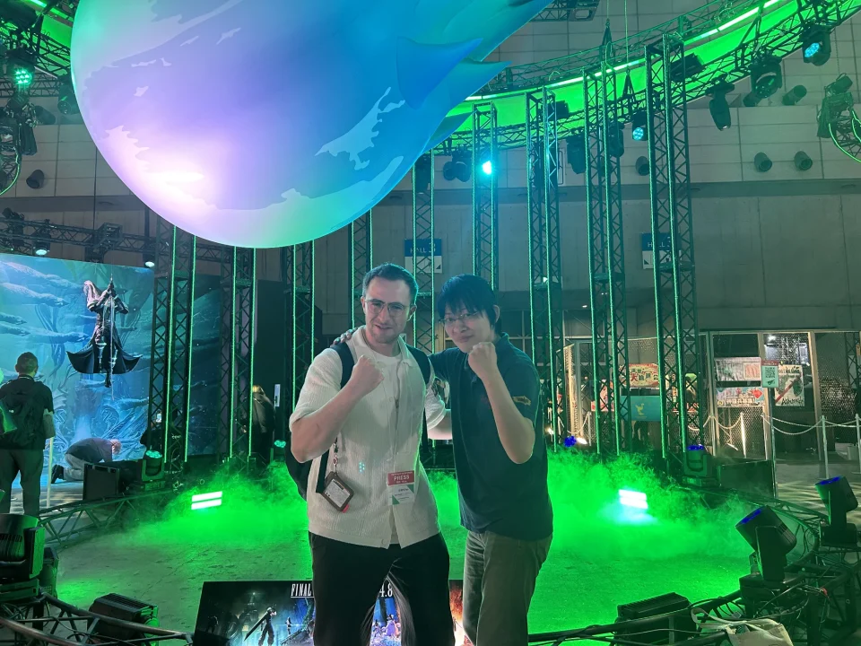 Matt Wardell and Naoki Hamaguchi in front of a large Meteor display for FInal Fantasy VII Revelation at TGS 2026.